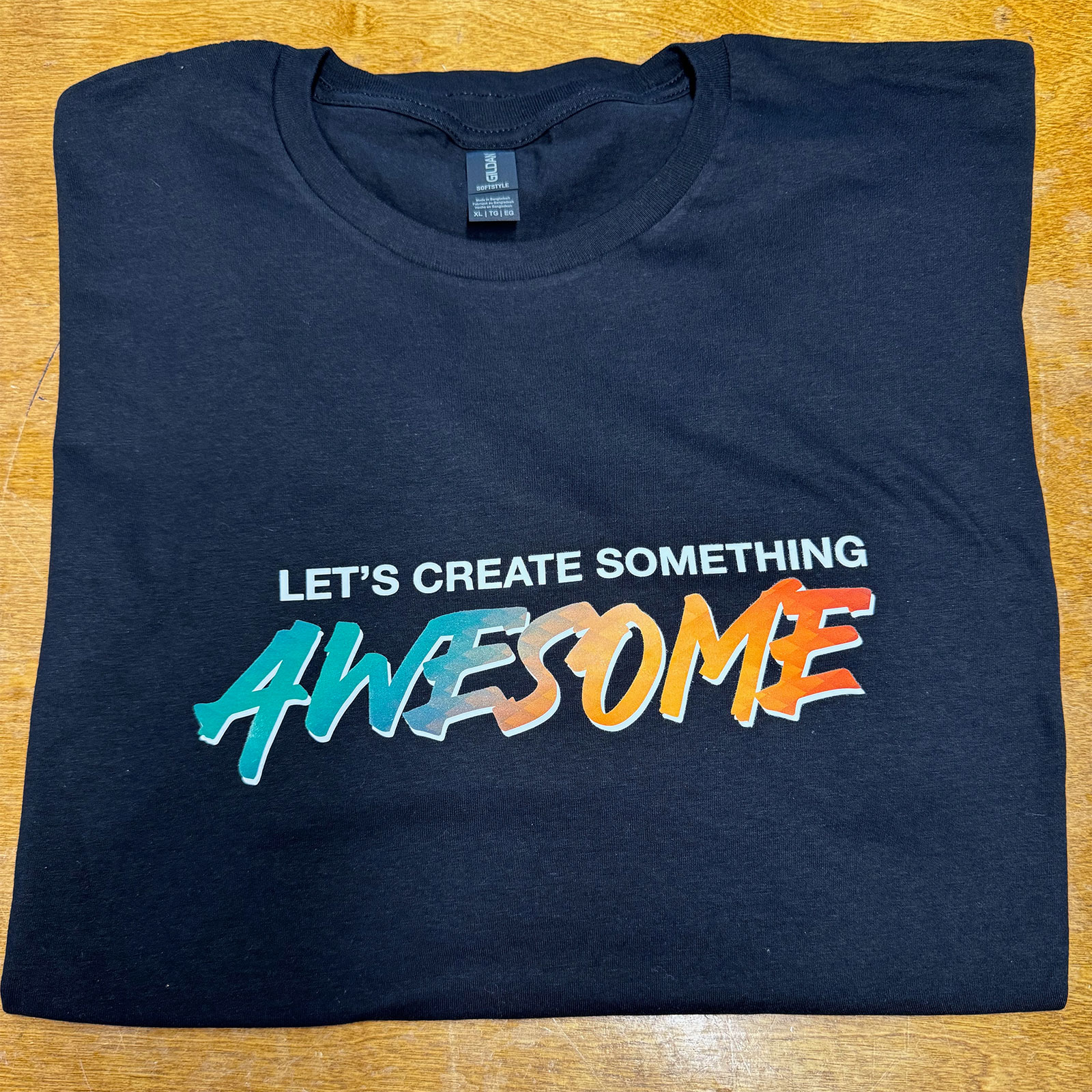 This is an image of a T-Shirt printed with Direct to Film that says Let's Create Something Awesome!