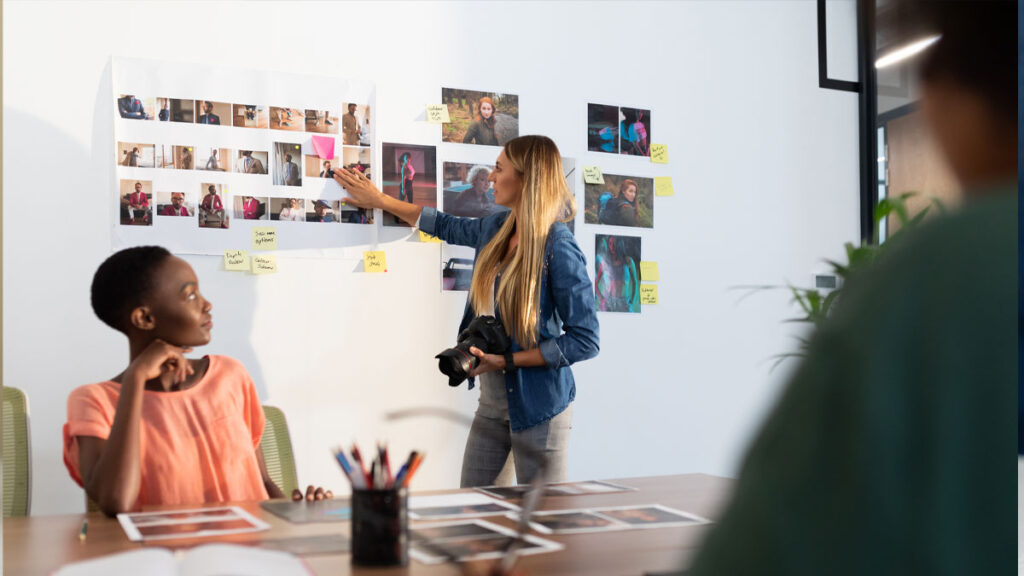 Diverse group of business colleagues brainstorming looking at photos in meeting room. 