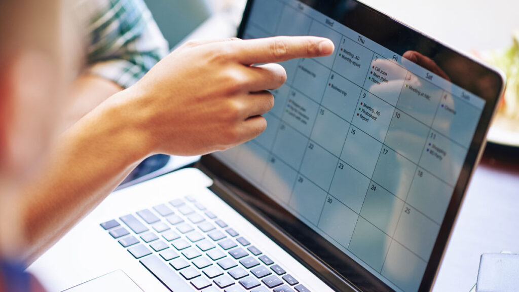 Close-up image of production team discussing working calendar for a month on laptop screen