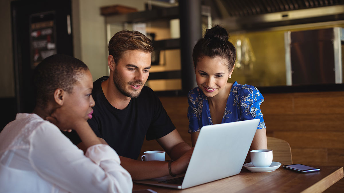 Man using laptop to show 2 women SEO result in coffee shop